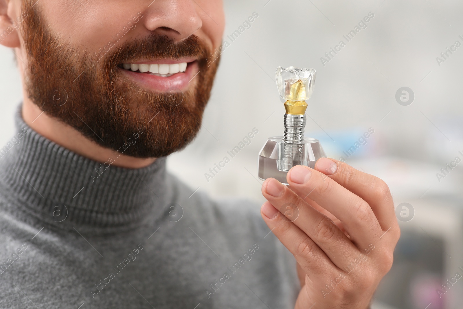 Photo of Man holding educational model of dental implant on blurred background, closeup