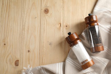 Salt and pepper shakers on wooden table, flat lay. Space for text