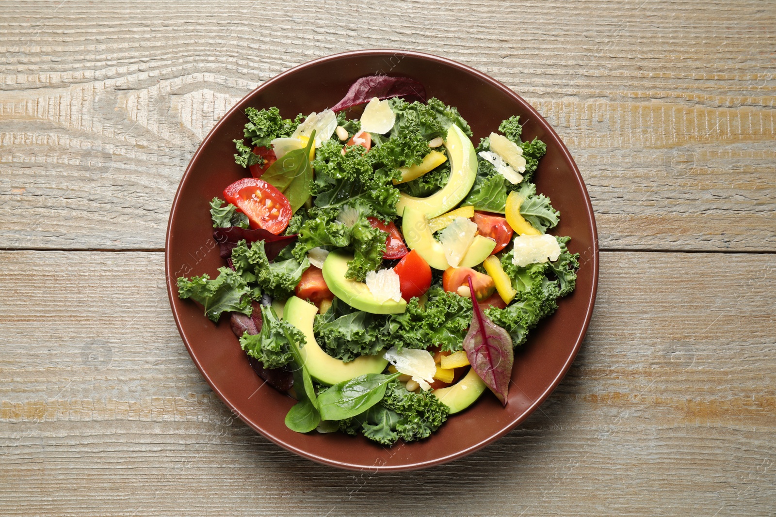 Photo of Tasty fresh kale salad on wooden table, top view