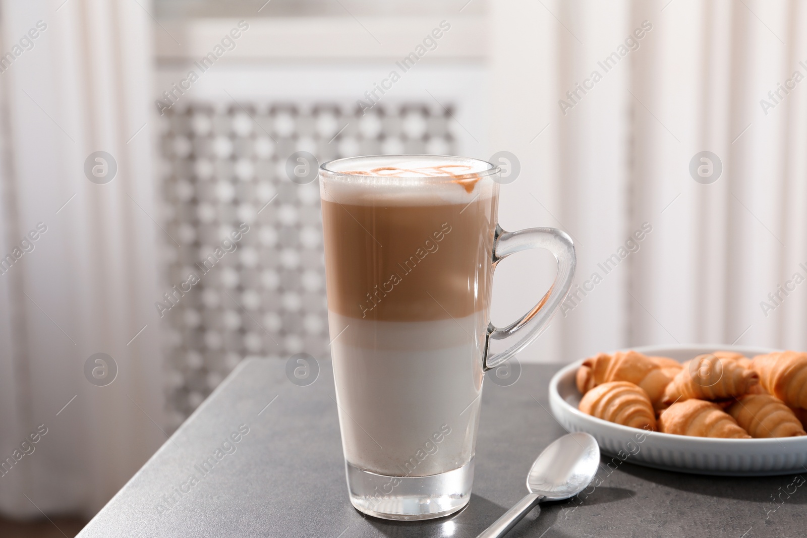 Photo of Glass cup of caramel macchiato and tasty pastry on table