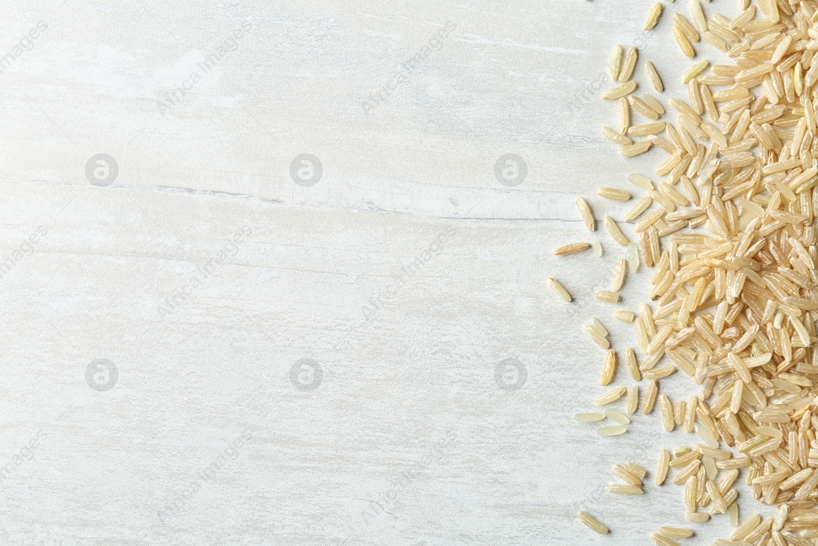 Photo of Brown rice on wooden background, top view with space for text