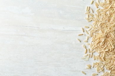 Brown rice on wooden background, top view with space for text