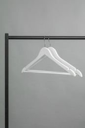 Photo of Empty clothes hangers on rack against grey background