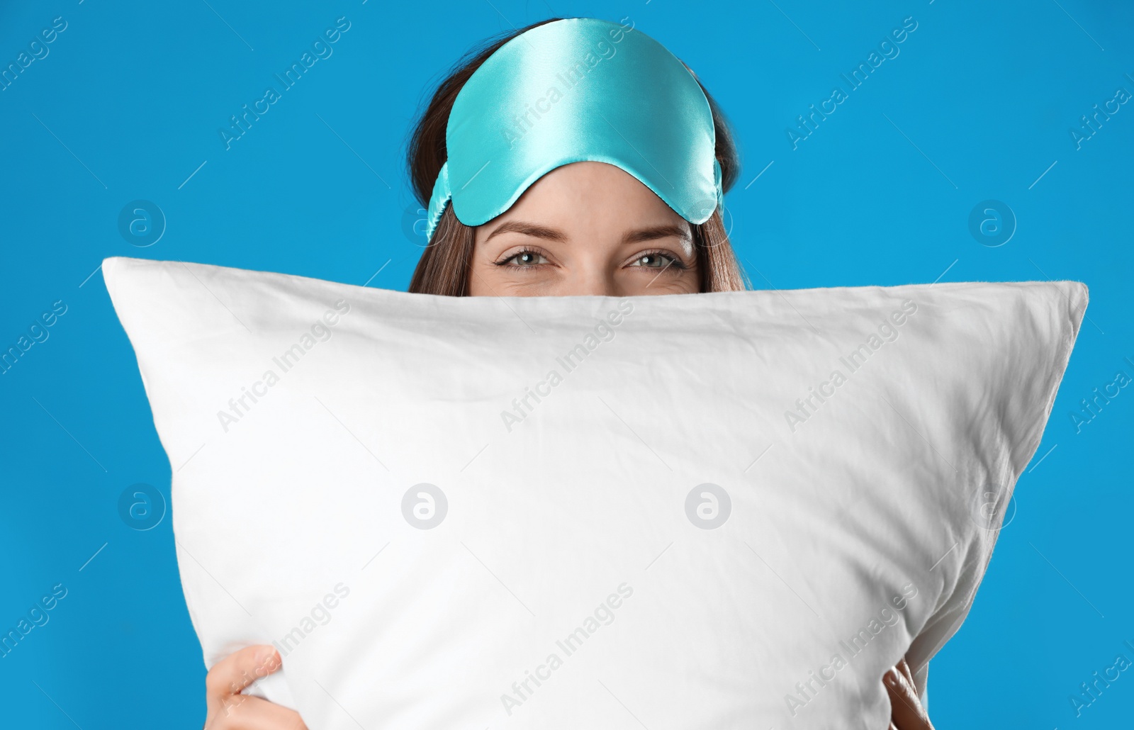 Photo of Beautiful woman with pillow on light blue background. Bedtime