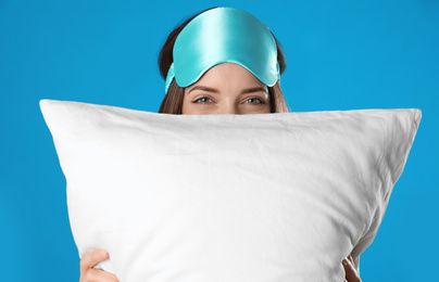 Beautiful woman with pillow on light blue background. Bedtime