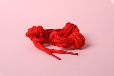 Photo of Red shoe lace on light pink background