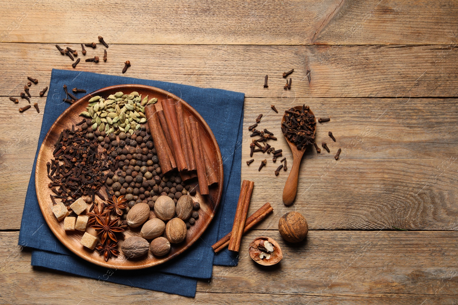 Photo of Spoon with different spices and nuts on wooden table, flat lay. Space for text