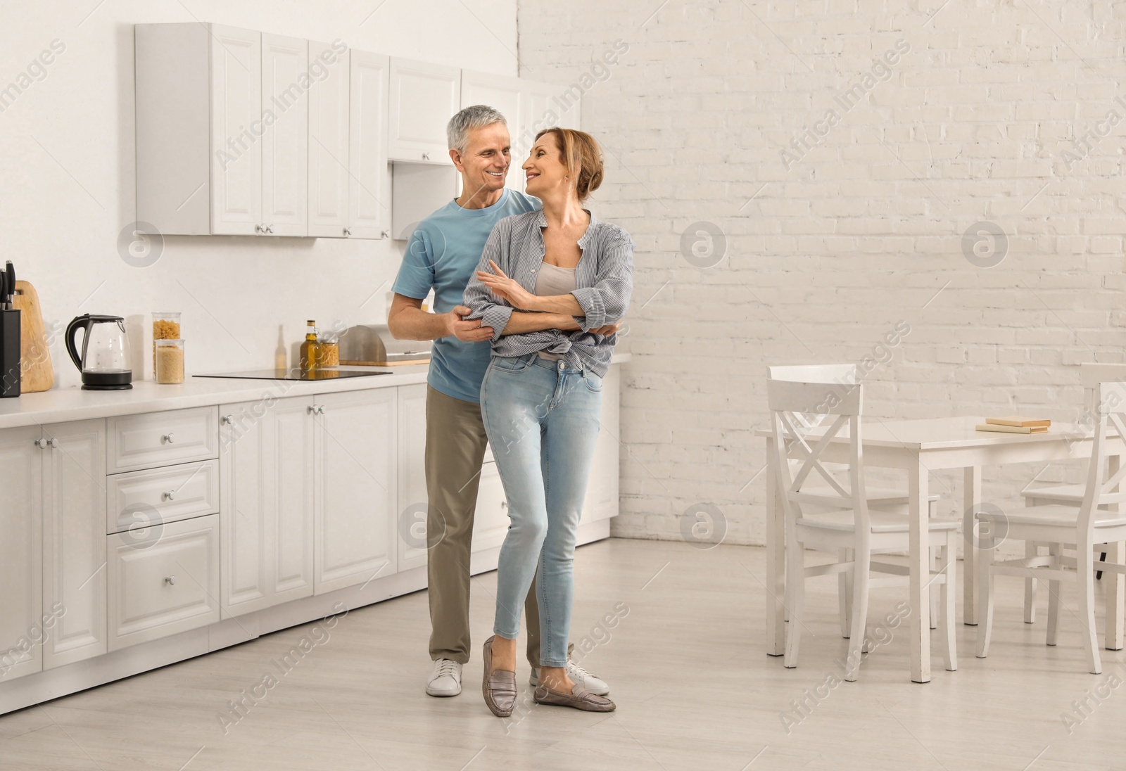 Photo of Happy senior couple dancing together in kitchen