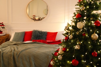 Beautiful decorated Christmas tree with fairy lights in bedroom. Interior design
