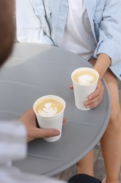 Coffee to go. Couple with paper cups at grey table outdoors, closeup