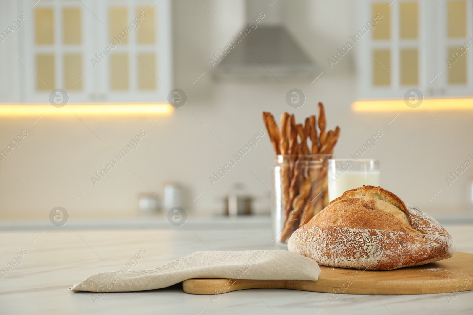 Photo of Loaf of bread on white table in kitchen. Space for text