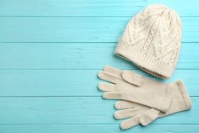 Photo of Stylish gloves and hat on turquoise wooden background, flat lay. Space for text