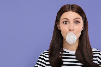 Photo of Beautiful woman blowing bubble gum on light purple background, space for text