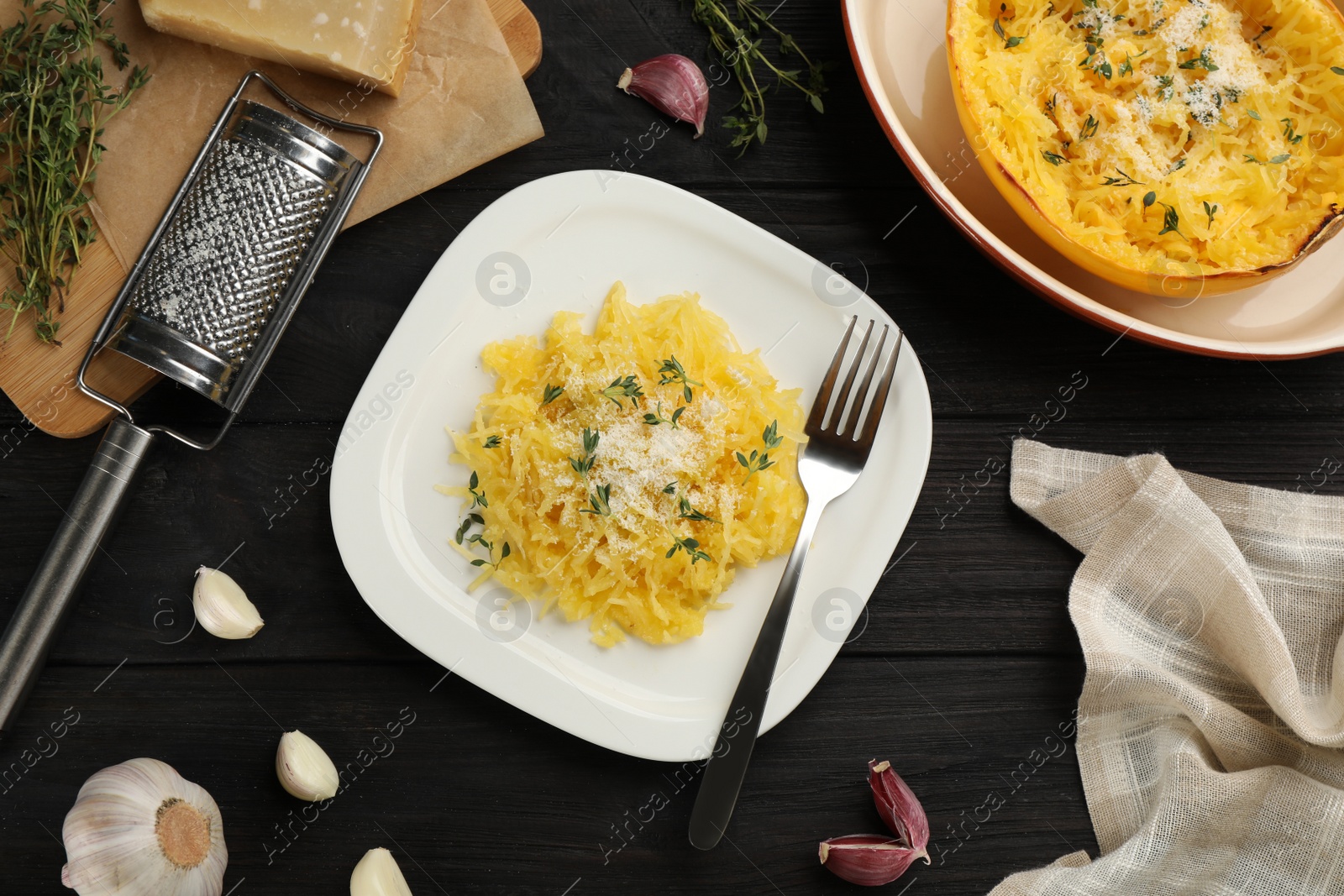 Photo of Tasty spaghetti squash with cheese and thyme served on black wooden table, flat lay