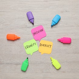 Photo of Sticky notes with words Diversity, Equality, Inclusion and markers on wooden table, flat lay