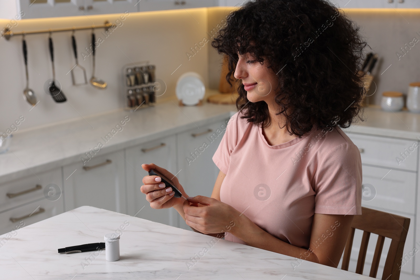 Photo of Diabetes. Woman checking blood sugar level with glucometer at white marble table in kitchen