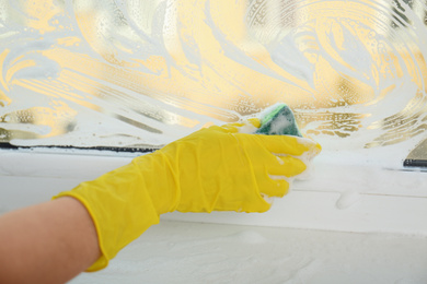 Photo of Woman cleaning window with sponge, closeup view