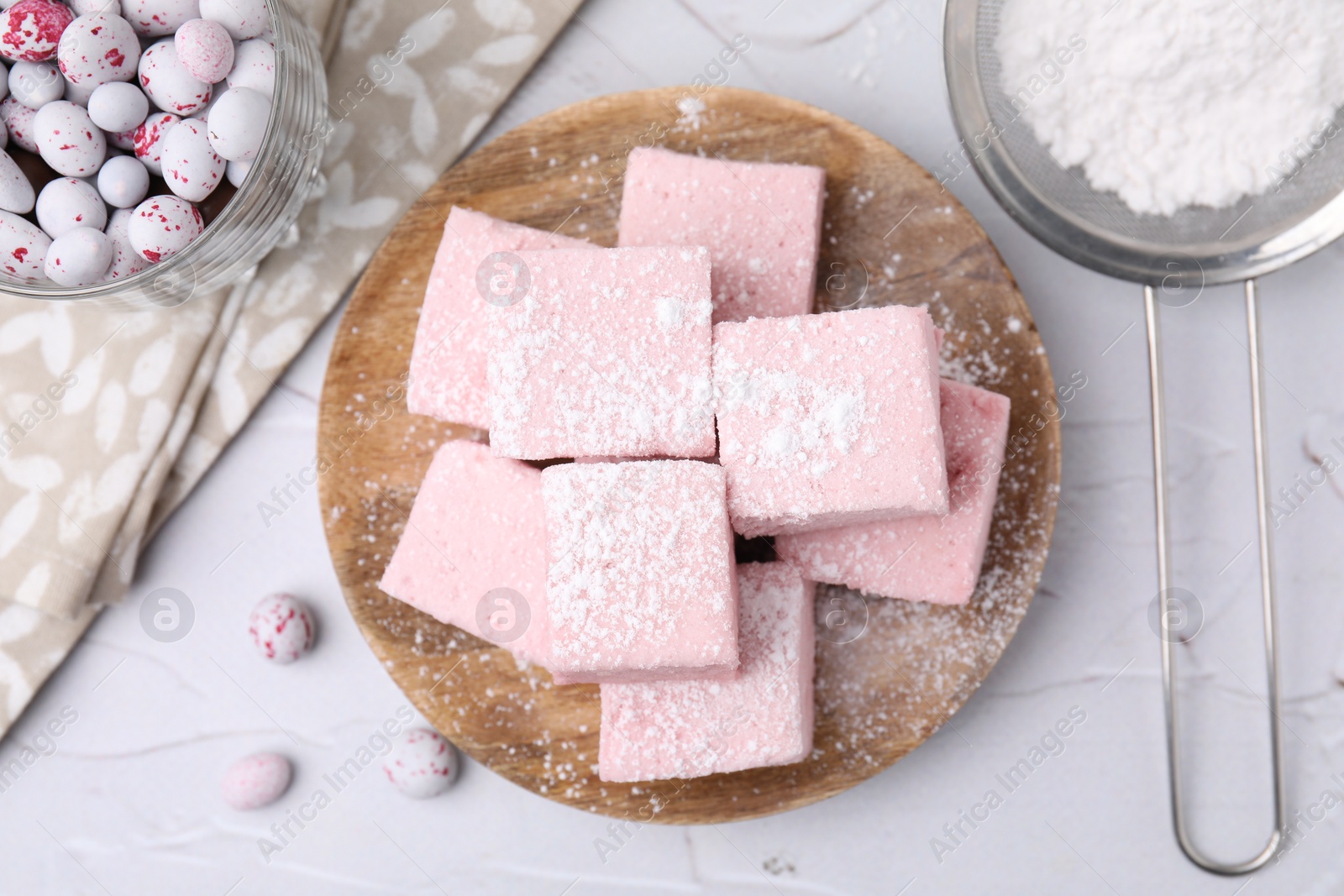 Photo of Tasty marshmallows with powder sugar on white textured table, flat lay