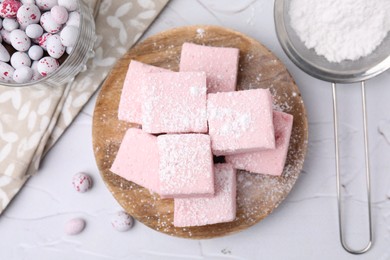 Tasty marshmallows with powder sugar on white textured table, flat lay