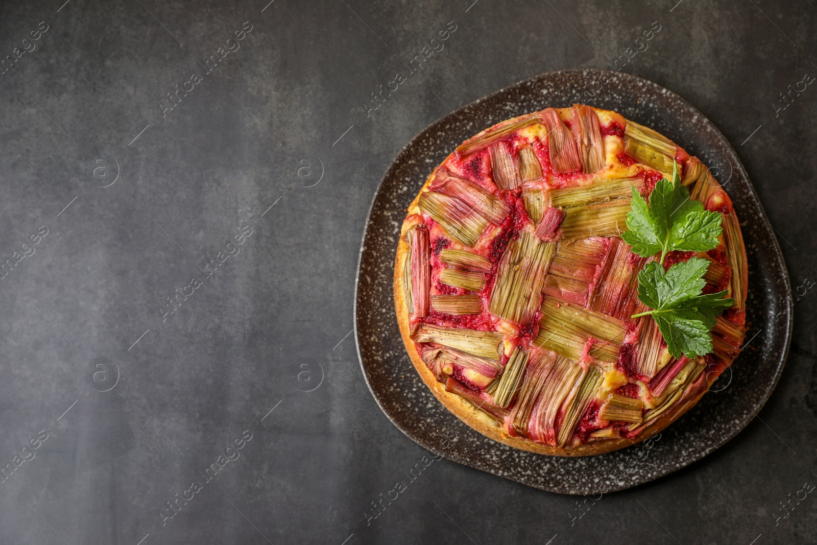 Photo of Freshly baked rhubarb pie on black table, top view. Space for text