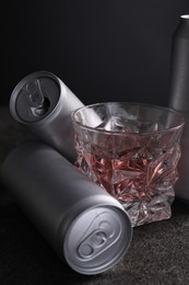 Photo of Energy drink in glass and aluminium cans on grey table, closeup