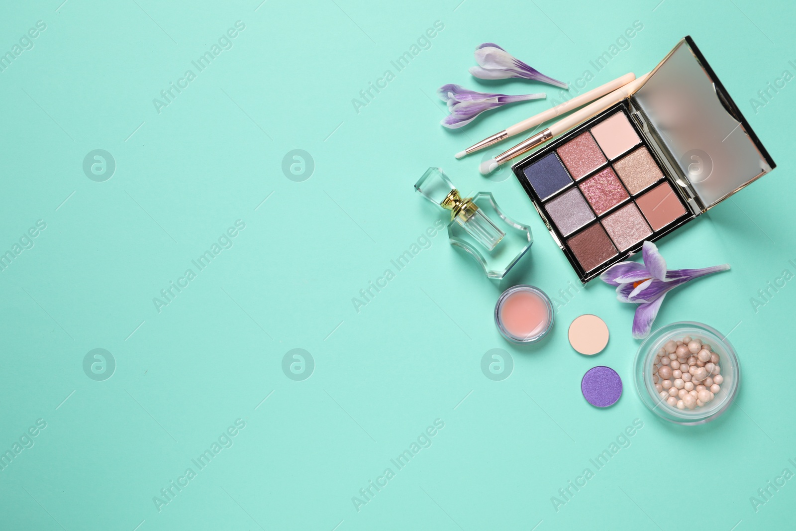 Photo of Flat lay composition with different makeup products and beautiful flowers on light turquoise background. Space for text