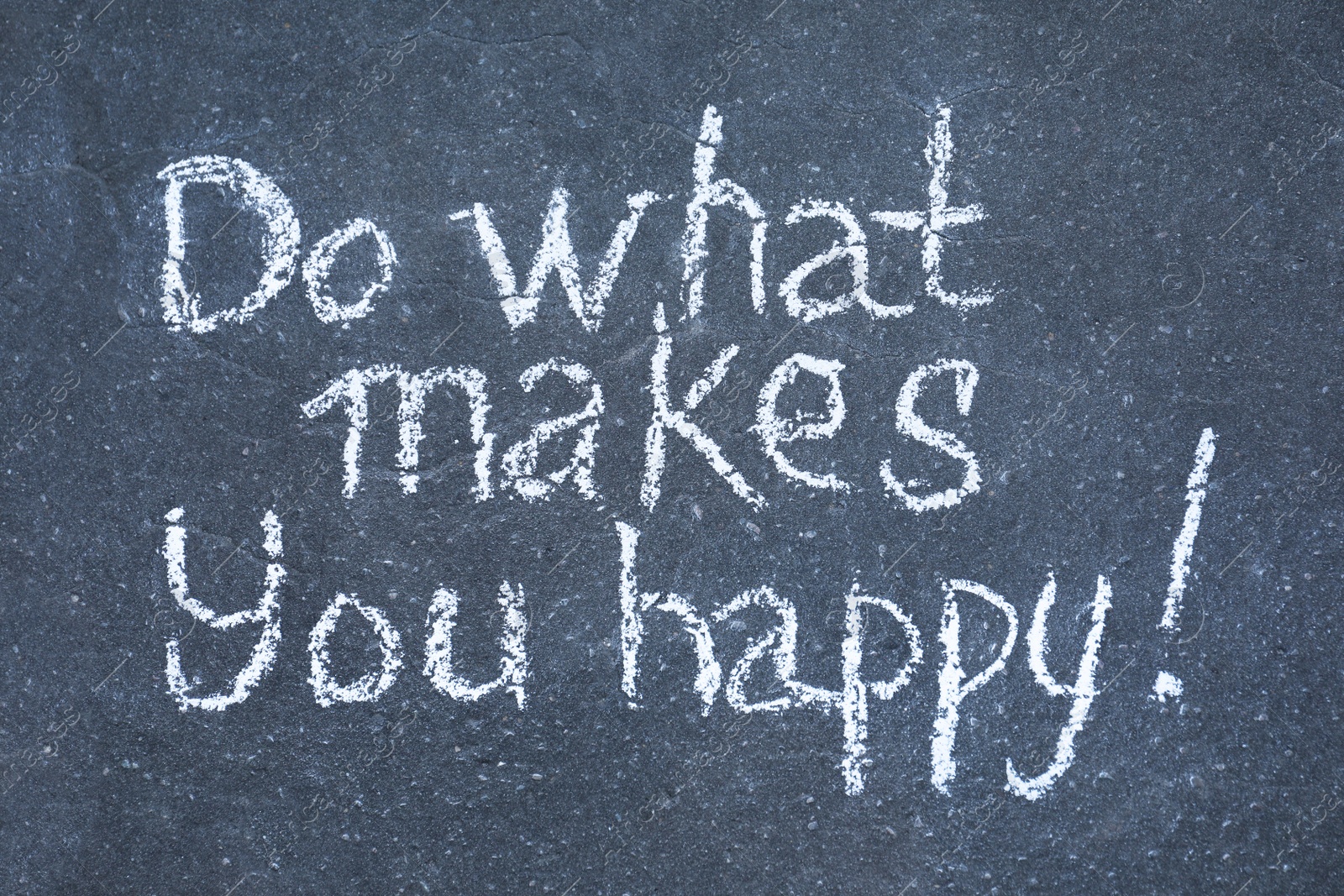 Photo of Phrase Do What Makes You Happy with exclamation mark written on asphalt, top view
