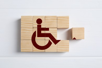 Image of Inclusion concept. Making international symbol of access with wooden cubes on white background, top view