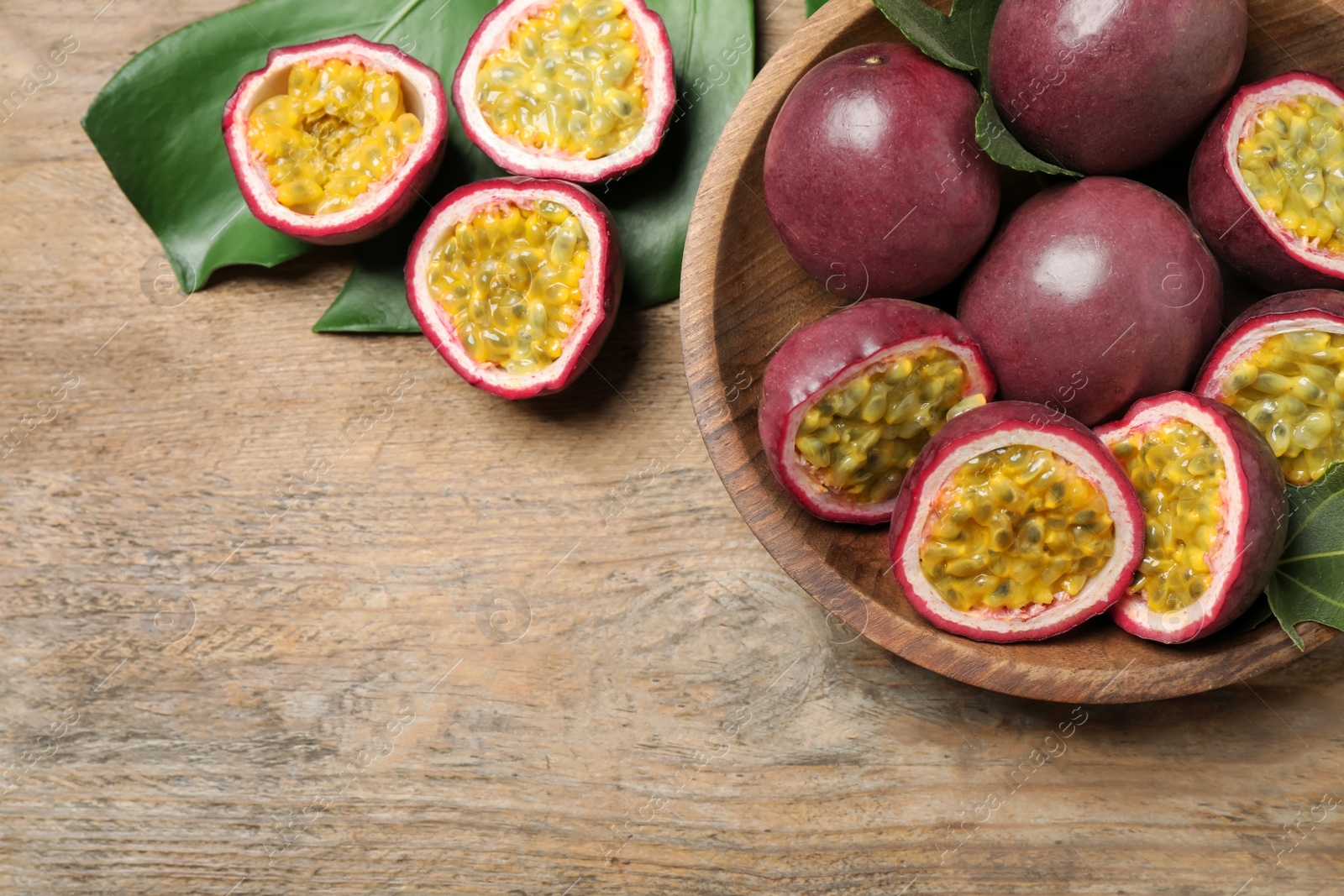 Photo of Cut and whole passion fruits (maracuyas) on wooden table, flat lay. Space for text