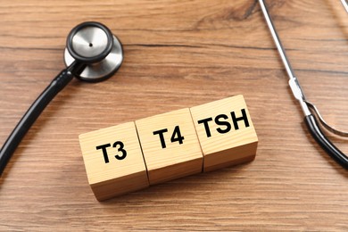 Photo of Endocrinology. Stethoscope and cubes with thyroid hormones on wooden table