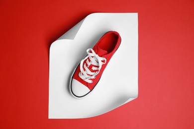 Photo of Red classic old school sneaker on color background, top view