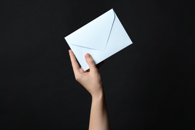 Woman holding white paper envelope on black background, closeup