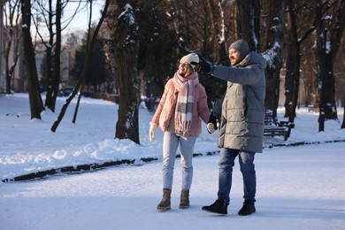 Happy couple walking in sunny snowy park. Space for text