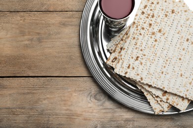 Photo of Traditional matzos and red wine on wooden table, top view. Space for text