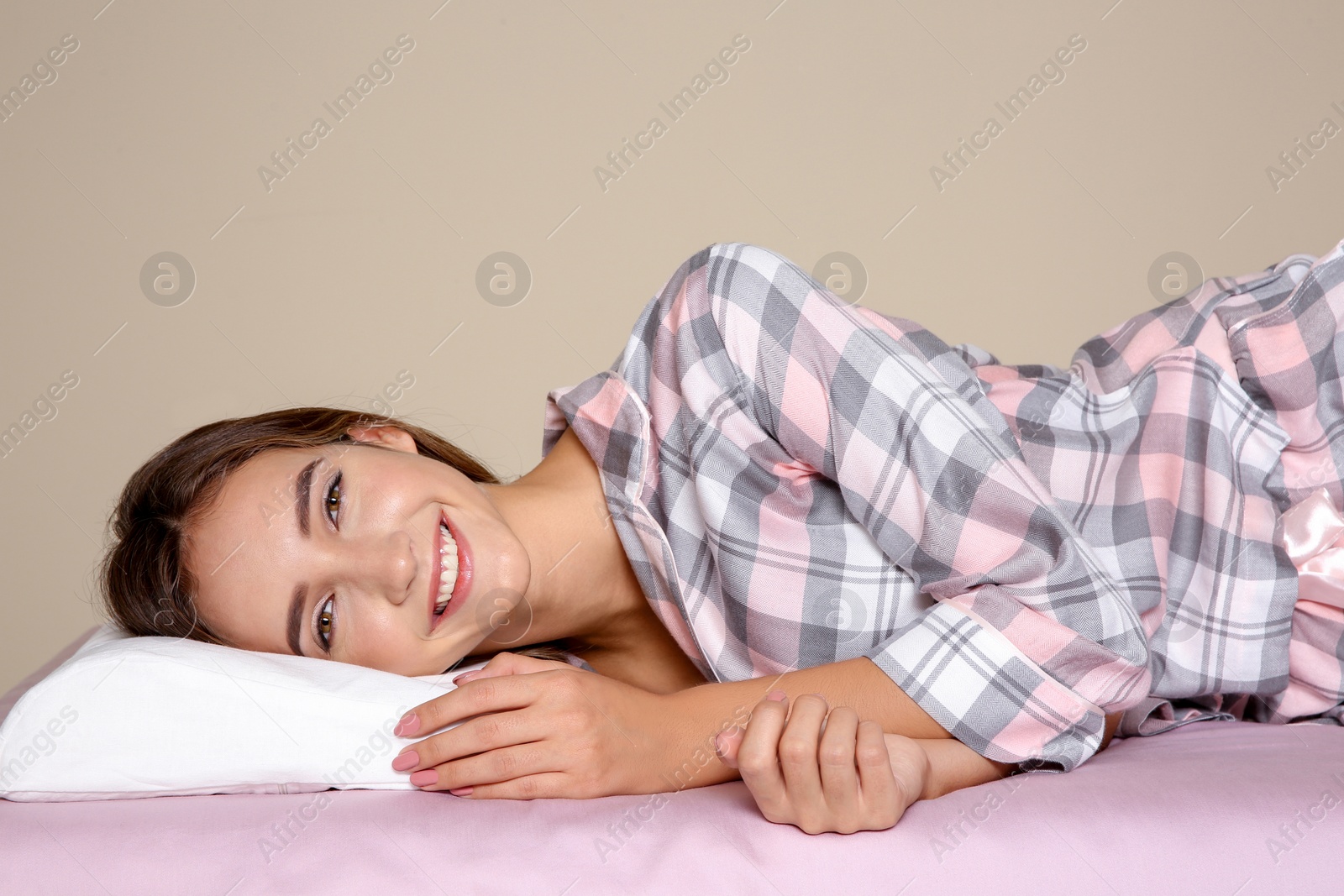 Photo of Beautiful teen girl lying with orthopedic pillow on bed against color background