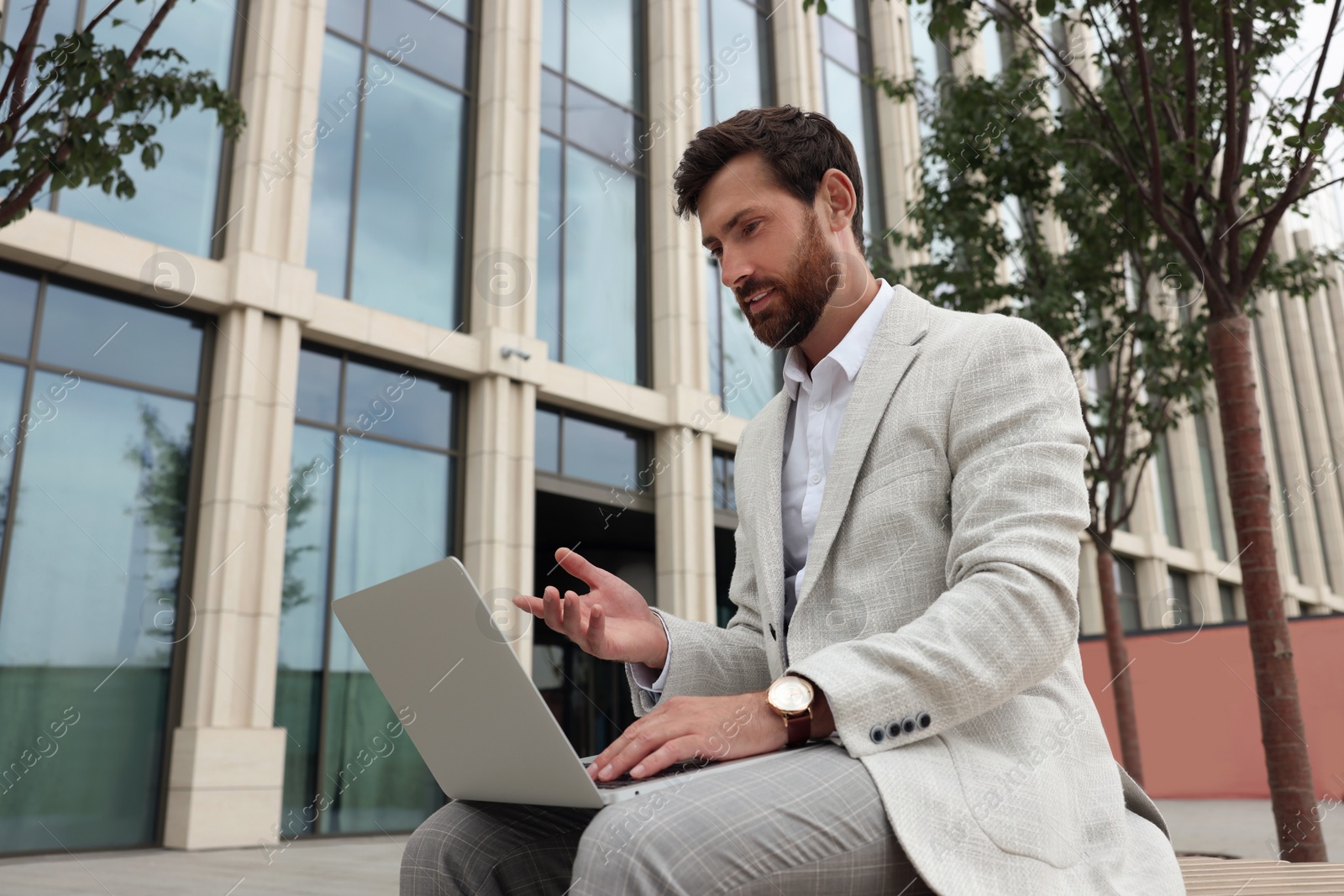 Photo of Handsome businessman with laptop on city street