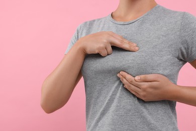 Photo of Woman doing breast self-examination on pink background, closeup