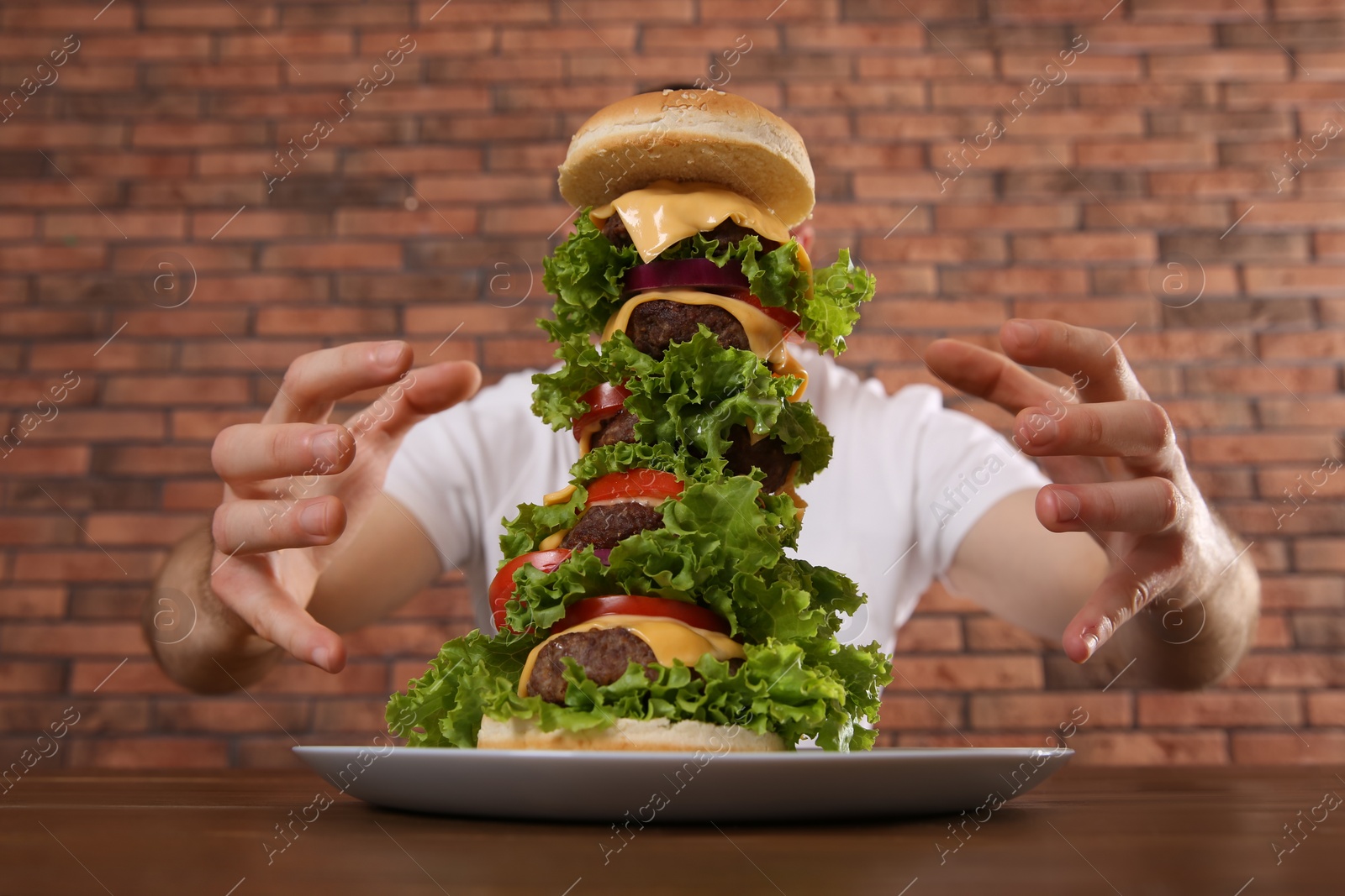 Photo of Hungry man with huge burger at wooden table