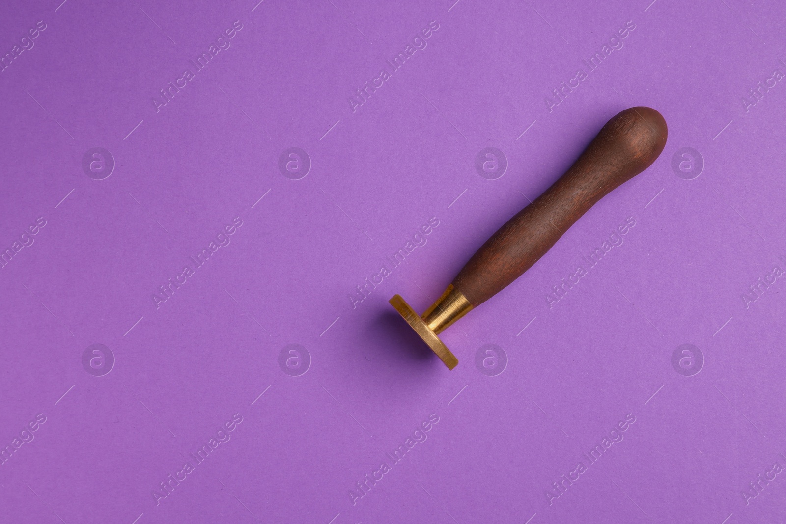 Photo of One stamp tool with wooden handle on purple background, top view. Space for text