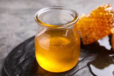 Tasty aromatic honey and combs on grey table, closeup