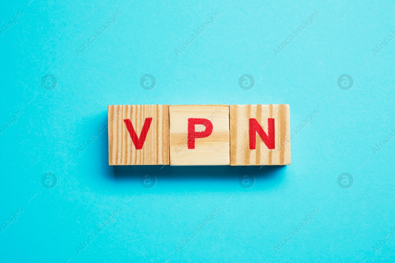 Photo of Wooden cubes with acronym VPN on light blue background, top view