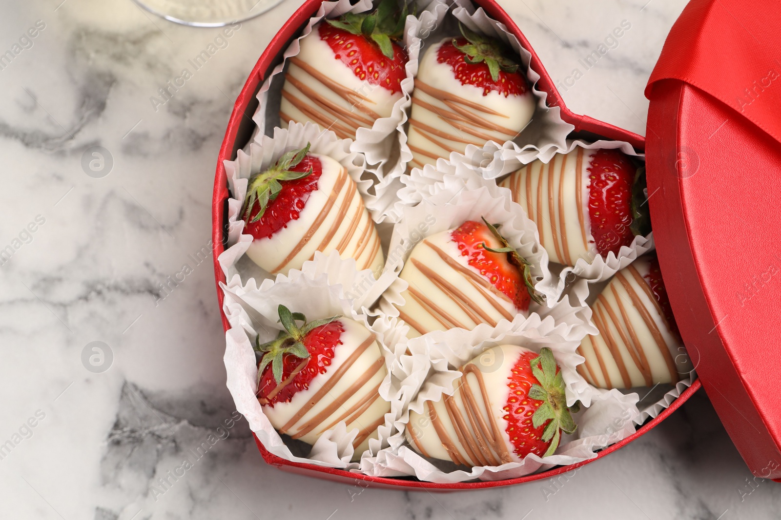 Photo of Heart shaped box with delicious chocolate covered strawberries on white marble table, top view