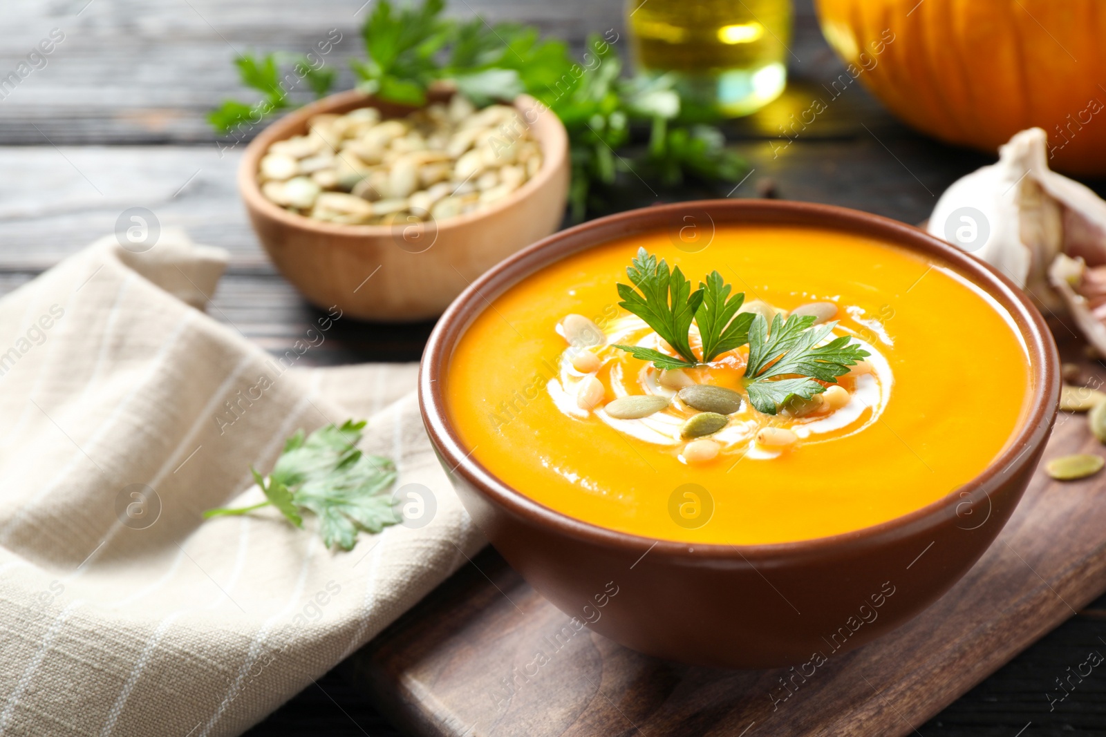 Photo of Delicious pumpkin soup in bowl on wooden table