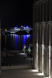 SPLIT, CROATIA - OCTOBER 08, 2023: Illuminated building near port with modern boats at night