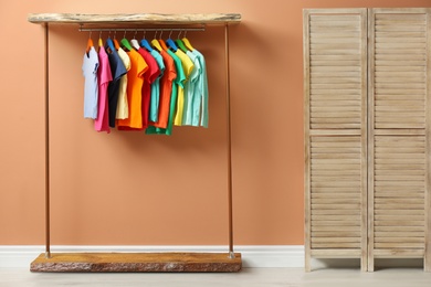 Rack with different child's clothes near coral wall