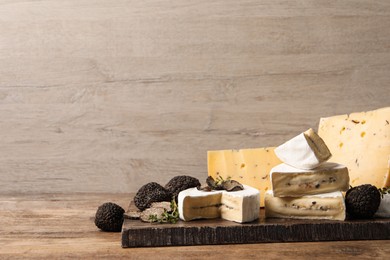Photo of Different types of cheese and truffles on wooden table, space for text