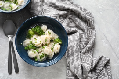 Photo of Tasty dumplings in broth served on grey marble table, top view. Space for text