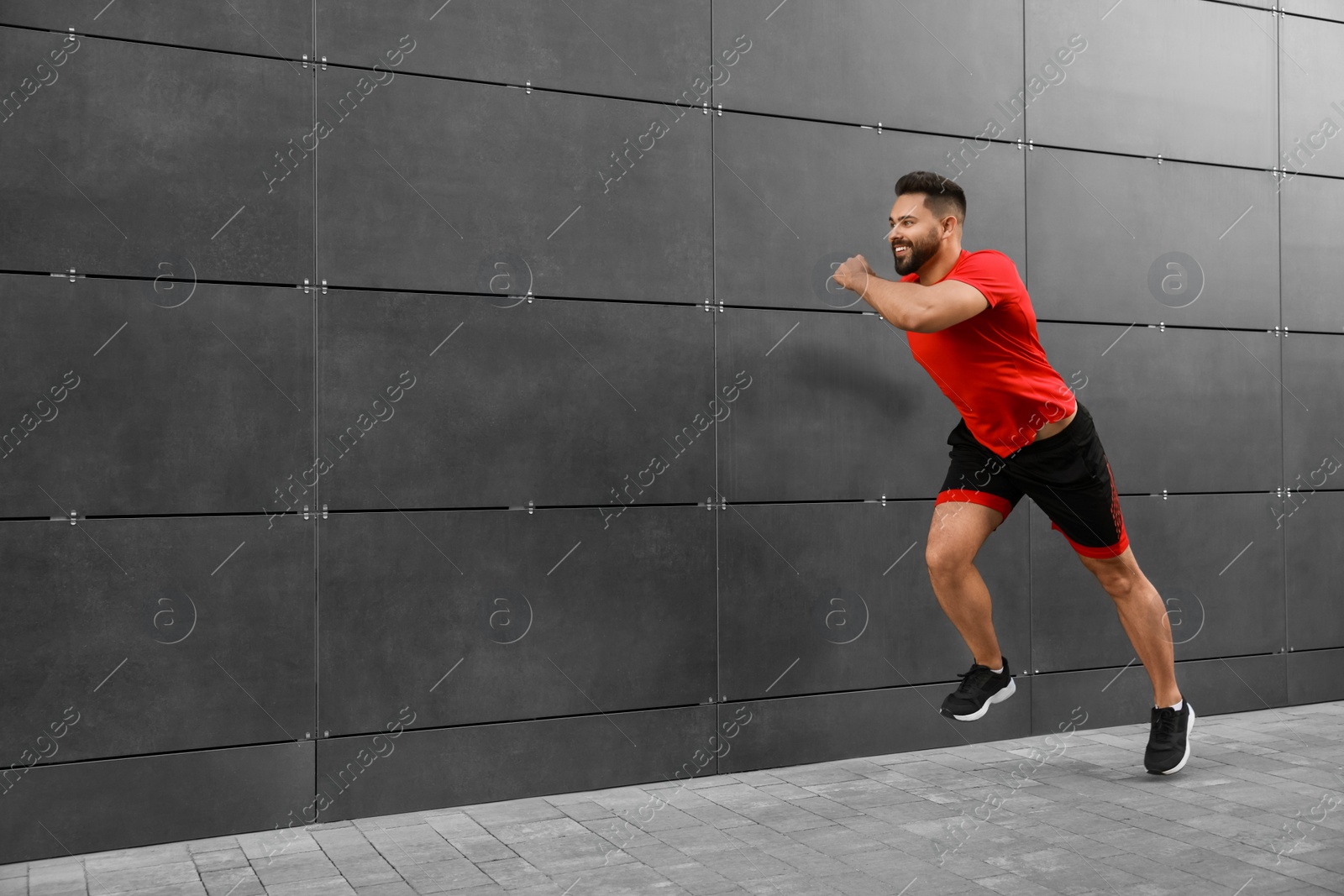 Photo of Happy man running near building outdoors. Space for text