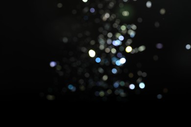 Blurred view of colorful festive lights on black background. Bokeh effect