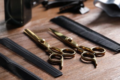 Photo of Hairdresser tools. Different scissors and combs on wooden table, closeup